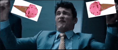 a man in a suit and tie is holding up two ice cream cones with pink scoops on them
