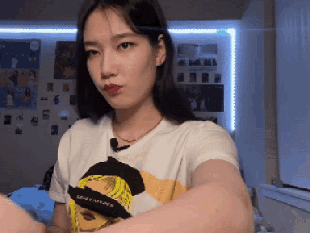 a woman wearing a white t-shirt with a picture of a girl on it looks at the camera