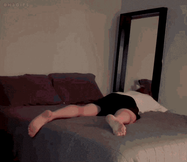 a person laying on their back on a bed in front of a large mirror