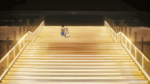 a couple of people standing on a set of stairs that are lit up at night
