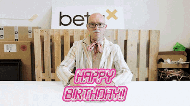 a man is sitting at a table with a sign that says " happy birthday "