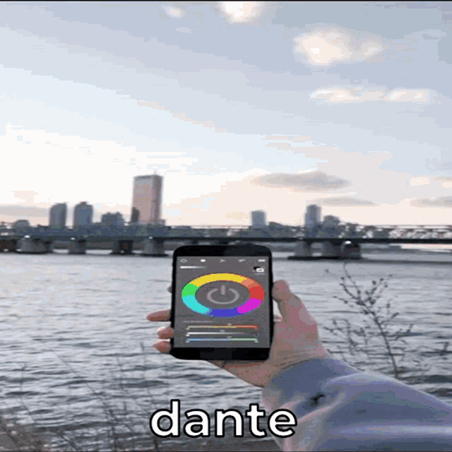 a person is holding a cell phone in front of a river and the word dante is on the bottom