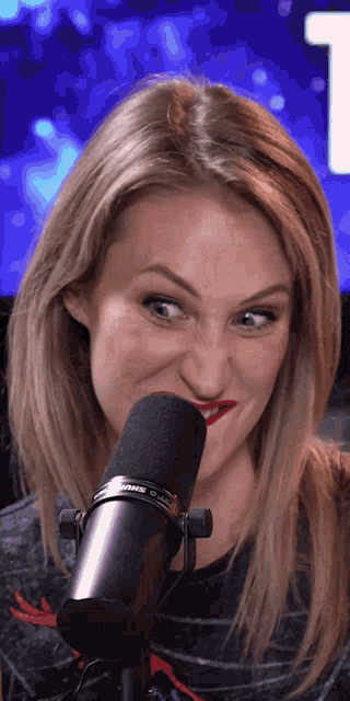 a woman is making a funny face in front of a shure brand microphone