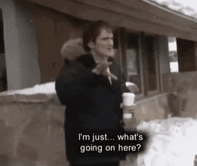 a man is standing in front of a house holding a cup of coffee and talking to someone .