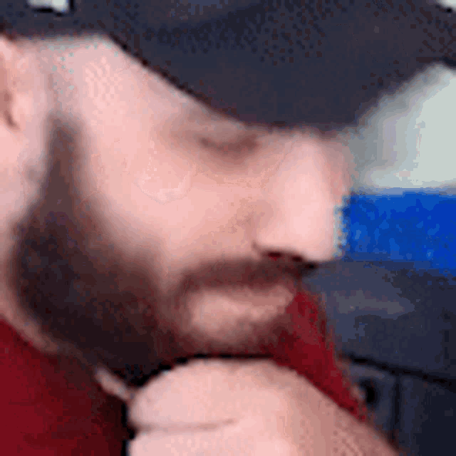 a man with a beard is wearing a hat and a red shirt