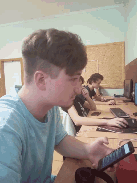 a man in a blue shirt is holding a cell phone