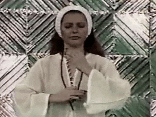 a woman in a white robe is standing in front of a green wall .