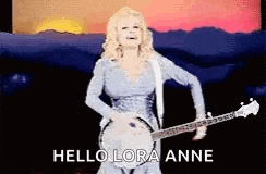 dolly parton is playing a banjo on stage and says hello lora anne .