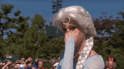 a woman dressed as elsa from frozen is covering her mouth with her hand