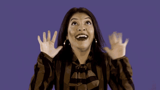 a woman in a striped shirt is making a funny face with her hands in the air