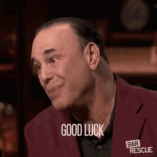 a man in a red jacket is smiling and saying good luck .
