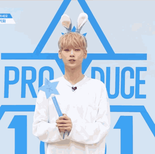 a boy wearing bunny ears is holding a wand in front of a blue background that says produce