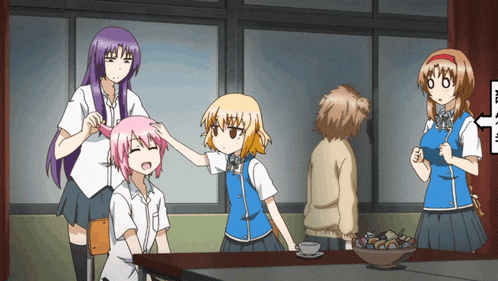 a group of anime girls are standing around a table with a sign that says ' a ' on it
