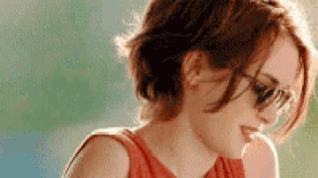 a close up of a woman wearing sunglasses and a red tank top .