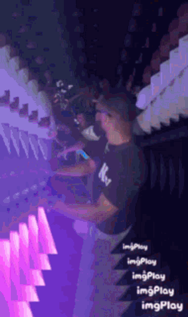 a man in a ny shirt is playing a keyboard in a dark room
