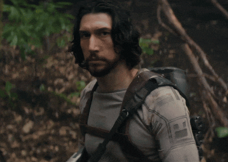 a man with long hair and a beard is wearing a backpack and a shirt that has the letter h on it