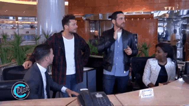 a group of people standing around a desk with a sign that says plus on it