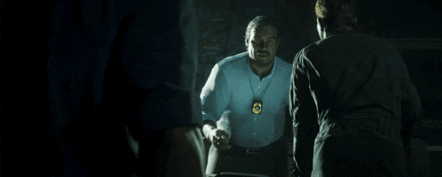 a man in a blue shirt has a badge around his neck with the letter c on it