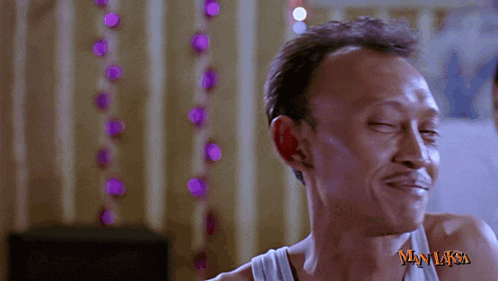 a man in a white tank top with the word man laksa on his chest