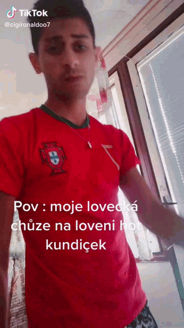 a man wearing a red shirt with a portuguese crest on it