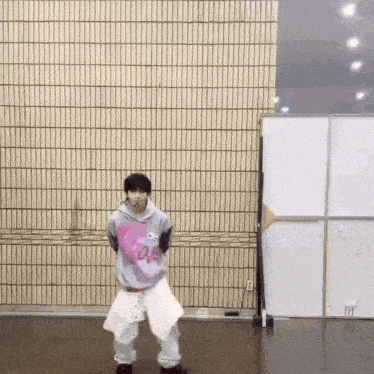 a young man is dancing in a room in front of a wall .
