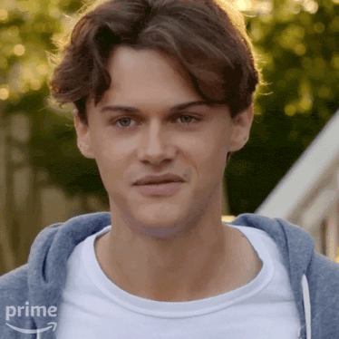a young man wearing a blue hoodie and a white t-shirt with an amazon prime logo on the bottom