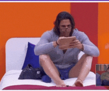 a man is sitting on a bed looking at a tablet with edairan written on the bottom