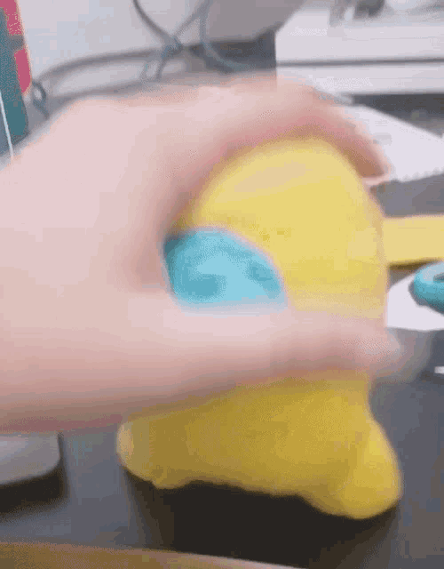 a person is holding a yellow stuffed animal with a blue head