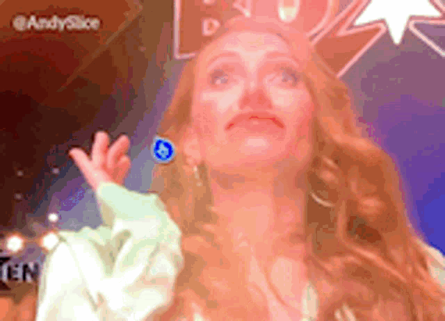 a woman with red hair is wearing blue earrings and a white shirt