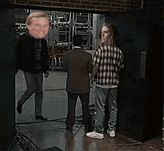 a man with a face on his head is standing next to a woman and a man in a plaid shirt