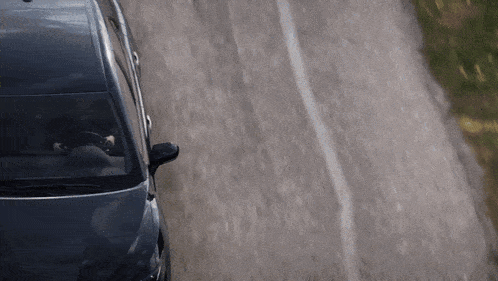 a black car is driving down a road with a white line on it