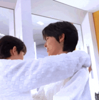 a couple of men hugging each other in front of a mirror .