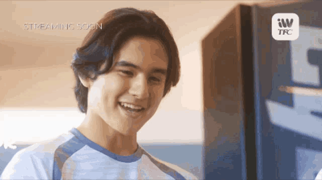 a young man is smiling in front of a refrigerator that says tfc on it