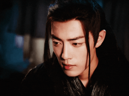 a close up of a young man with long black hair