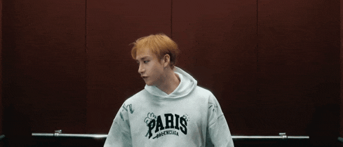 a young man with blonde hair is wearing a white hoodie with the letter x on it