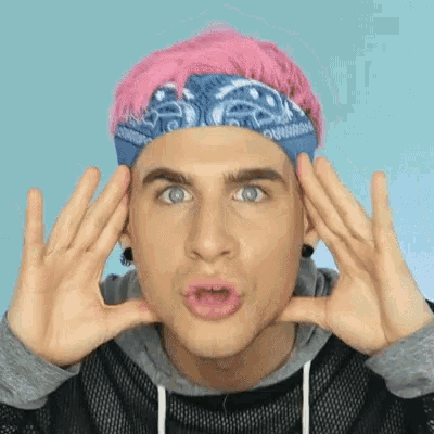 a man with pink hair and a bandana on his head making a face