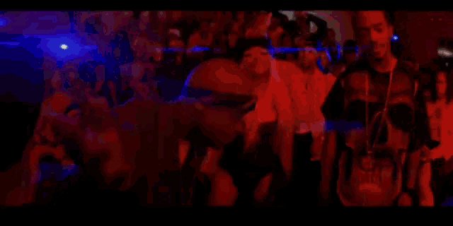 a group of people are standing in a dark room with a blue light behind them .