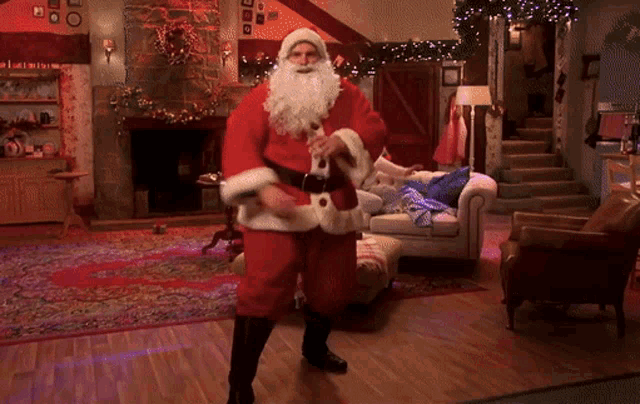 a man dressed as santa claus is dancing in a living room with a fireplace