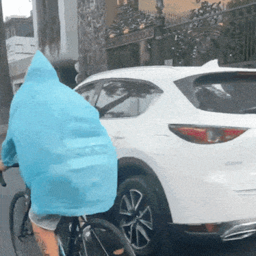 a person wearing a blue raincoat is riding a bike