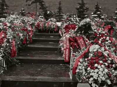 a cemetery filled with flowers and red ribbons with the word " cccp " on them