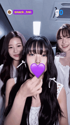 a girl with a purple heart in her mouth is surrounded by two other girls