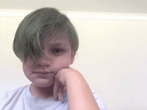 a young boy with green hair has his hand on his face
