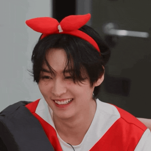 a young man wearing a red bow on his head smiles