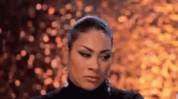 a woman in a black turtleneck is making a funny face in front of a blurry background .
