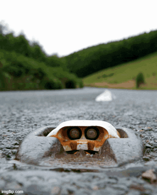 a close up of a metal object on a road with imgflip.com written below it