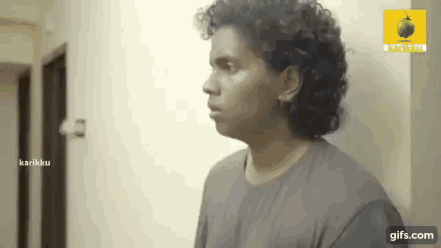 a man with curly hair is standing in a hallway next to a sign that says karikku