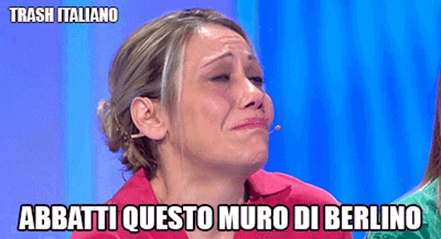 a woman is crying with the words abbatti questo muro di berlino on the bottom