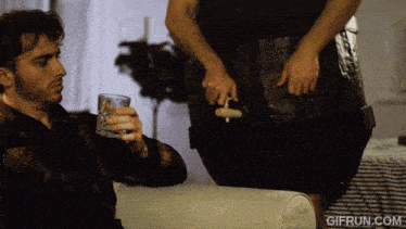 a man sitting on a couch with a glass of water and a gifrun.com watermark