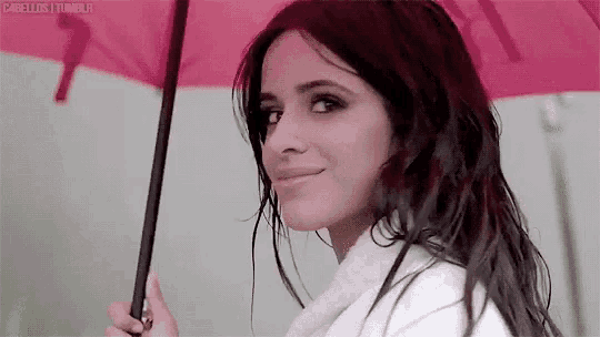 a woman in a white coat is holding a pink umbrella in the rain .