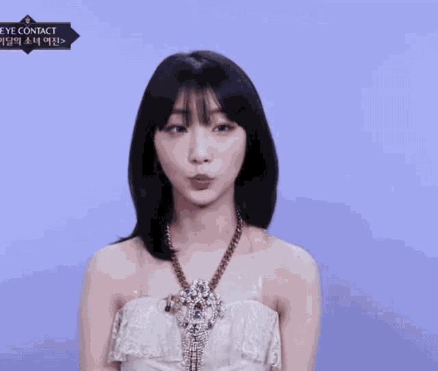a woman in a white dress stands in front of a blue background that says eye contact on it